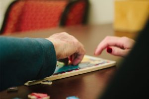 A woman puts together a puzzle at a skilled nursing facility