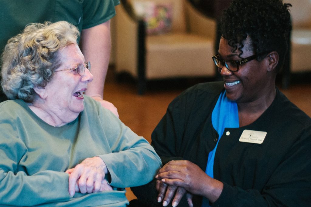 A nurse and and resident at a skilled nursing facility smiling at each other